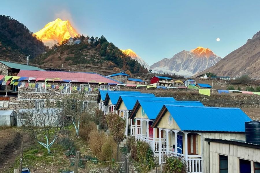 Colorful village buildings with blue roofs at sunrise in mountain valley